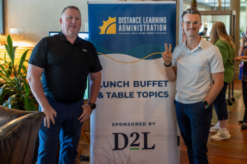Two men stand beside a DLA Lunch Buffet and Table Topics banner.