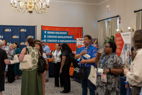 People walk around visiting booths in an auditorium.