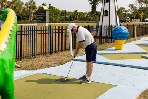 A man lines up a shot with a golf club in a colorful golf course.